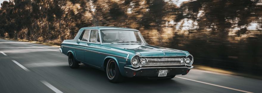 teal sedan on roadway beside the trees