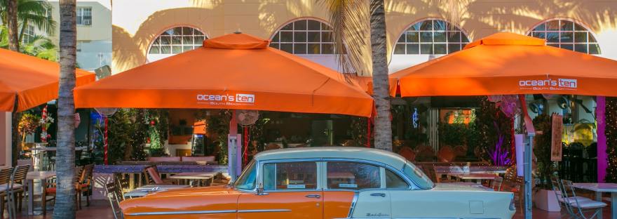 orange and white vintage car parked beside palm tree during daytime