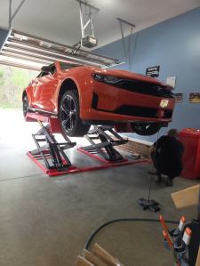 Orange sports car on a scissor lift in a customer garage featured by Olympic Equipment
